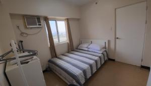 a small bedroom with a bed with a window at Manila Sunset View in Manila