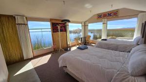 a bedroom with two beds and a view of the water at Uros Sunset Lodge in Puno