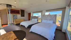 a bedroom with two beds and a table and a window at Uros Sunset Lodge in Puno