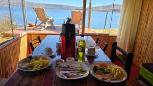 a table with two plates of food and a view of the ocean at Uros Sunset Lodge in Puno