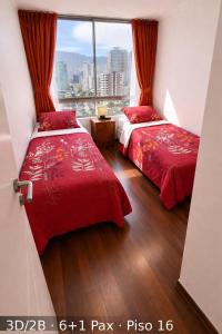 two beds in a room with a window at Departamentos Nautilus in Iquique
