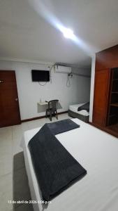 ein Schlafzimmer mit zwei Betten, einem Fernseher und einem Stuhl in der Unterkunft Hotel oriente in Maicao