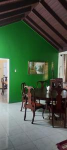 a dining room with a green wall and a table and chairs at Tambell Haven in Runaway Bay