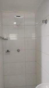 a bathroom with a shower with white tile at Suites Clarinda in Capitólio