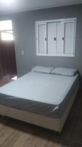 a large bed in a bedroom with a window at Suites Clarinda in Capitólio