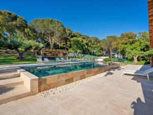 a swimming pool with benches and trees in the background at Vue Saint Tropez in Grimaud