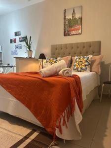 a bedroom with a large bed with an orange blanket at Vila Noel Centro in Penedo