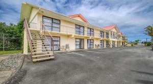 a building with a staircase in a parking lot at Wayfarer Motel in Kaitaia