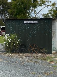a black shed with a sign that reads shower is block at Waitomo Farmstay - Kiwi Cabin 5 in Waitomo Caves