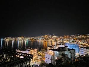a view of a city at night with the water at Duplex Penthouse with Jacuzzi in Sarandë