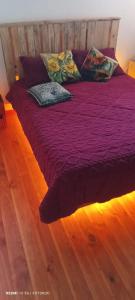 a bed with purple sheets and pillows on a wooden floor at Refugio del Pirata Algarrobo in San Antonio