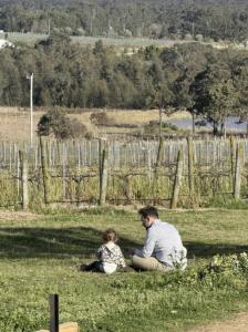 a man and a child sitting in the grass at Whispering Vines in Lovedale