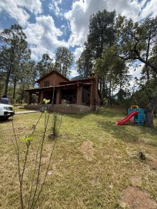 a house with a yard with a playground at Cabaña Cuevas Tapalpa in Tapalpa