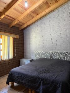 a bedroom with a bed and a brick wall at Cabaña Cuevas Tapalpa in Tapalpa