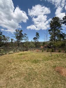 a field with a fence and trees in the background at Cabaña Cuevas Tapalpa in Tapalpa +3 photos