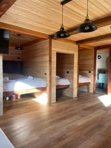 two beds in a room with wooden walls at Tiny Under Chalet in Santiago