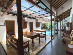 a dining room with a table and benches and a pool at Sabi House Kates in Timuran