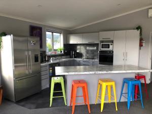 a kitchen with four colorful stools at a counter at Modern Spacious Manapouri Home in Manapouri