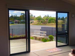 a sliding glass door with a bench on a deck at Modern Spacious Manapouri Home in Manapouri