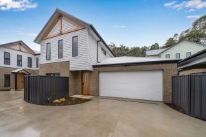 a house with white garage doors in a driveway at New central three bed townhouse in Beechworth