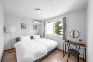 a bedroom with a bed and a desk and a window at Asahikawa Stay Ecole 101 in Asahikawa