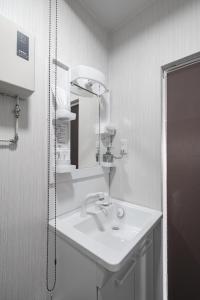 a white bathroom with a sink and a mirror at Asahikawa Stay Ecole 101 in Asahikawa