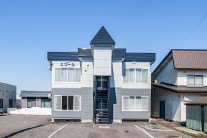 a white building with a black roof at Asahikawa Stay Ecole 101 in Asahikawa