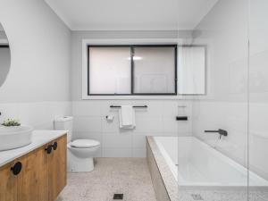 a white bathroom with a toilet and a sink at New central three bed townhouse in Beechworth +18 photos