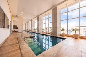 a swimming pool in a building with windows at Apartamento Moderno Premium - Cittyplex in Osasco