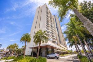 a car parked in front of a tall building with palm trees at Apartamento Moderno Premium - Cittyplex in Osasco