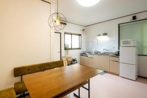 a kitchen with a wooden table and a refrigerator at あわら湯のまち駅から徒歩3分の湯の花ハウス in Awara