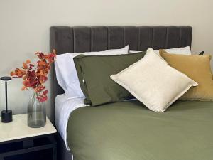 a bed with many pillows and a vase of flowers on it at Central brand new studio in Beechworth