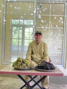 a man sitting at a table with two plates of grapes at Village Homestay in Chalt +5 photos
