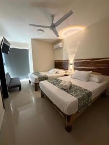 a hotel room with two beds and a ceiling fan at Hotel Urban Tacana in Tapachula