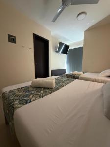 a hotel room with two beds and a flat screen tv at Hotel Urban Tacana in Tapachula +2 photos
