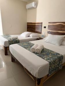 a hotel room with three beds with towels on them at Hotel Urban Tacana in Tapachula