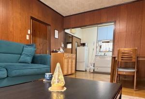 a living room with a blue couch and a table at 一棟貸の宿さくらんぼ in Kami-yuge