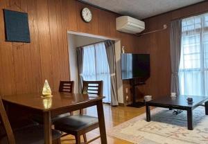 a dining room with a table and a clock on the wall at 一棟貸の宿さくらんぼ in Kami-yuge
