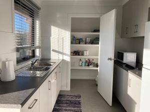 a white kitchen with a sink and a microwave at George Town Central Apartment in George Town