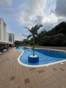 a pool with a palm tree in the middle of it at Oasis Villeta Apartamento in Villeta