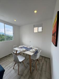 a white dining room with a table and chairs at Oasis Villeta Apartamento in Villeta