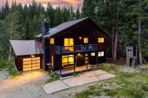 a large house with lights on in a forest at Slopeside Chalet on River Next To WP Resort I Fantastic Views I Private Hot Tub I Gas Firepit I Game Room I Activity Program in Winter Park