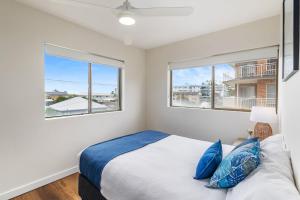 a bedroom with two windows and a bed with blue pillows at Sunset Reset in Soldiers Point