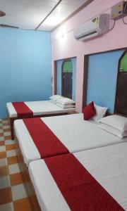 a room with three beds with red and white sheets at Hotel Vrindavan Near Prem Mandir Distance 15 min in Mathura