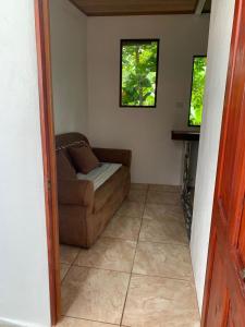 a living room with a couch and two windows at Hospedaje las rocas in Puerto Jiménez