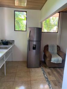 a kitchen with a stainless steel refrigerator and a chair at Hospedaje las rocas in Puerto Jiménez