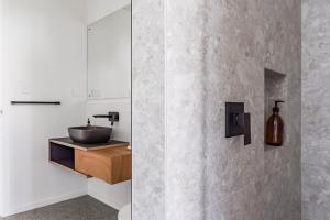 a bathroom with a sink and a concrete wall at On Point House, Luxury design, Water Views in Raglan