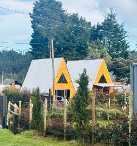 a yellow house with a fence in front of it at Cabañas The Twins in Medellín
