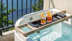 two glasses sitting on a tray on a balcony with a pool at Yeosu Bokja Spa Pension in Yeosu