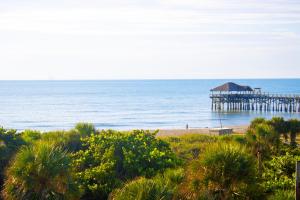 a pier on the beach next to the ocean at Cocoa Beach Towers - Oceanfront Resort with Heated Pool, Tennis Steps from the Pier in Cocoa Beach +42 photos